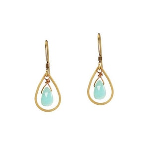 May include: A pair of gold teardrop earrings with a light blue gemstone in the center of each earring.