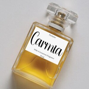 May include: A rectangular perfume bottle with a clear, faceted cap and a gold-coloured neck. The bottle contains a golden liquid and has a white label with the word "Carnia" in cursive. The label also includes the text "Perfume" and "With A Luxurious Fragrance 30 ml."
