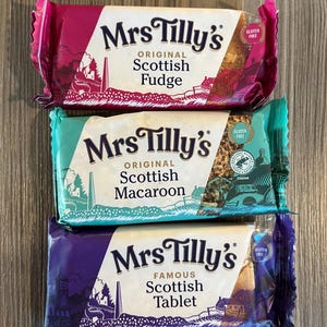 Pu&ograve; includere: Tre confezioni singolarmente avvolte di dolcetti scozzesi Mrs. Tilly's. La confezione superiore &egrave; rosa e dice "Original Scottish Fudge". La confezione centrale &egrave; blu e dice "Original Scottish Macaroon". La confezione inferiore &egrave; viola e dice "Famous Scottish Tablet".