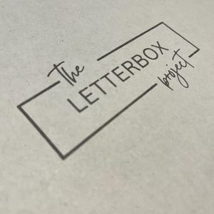Pu&ograve; includere: Una scatola bianca con il testo "The Letterbox Project" in una cornice quadrata nera.