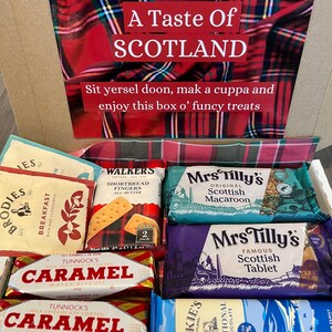 Pu&ograve; includere: Una scatola regalo in tartan rosso e verde piena di vari dolcetti scozzesi, tra cui dita di shortbread, cialde al caramello e tavolette di cioccolato. La scatola ha un'etichetta che dice "A Taste of Scotland" e "Sit yersel doon, mak a cuppa and enjoy this box o' funcy treats".