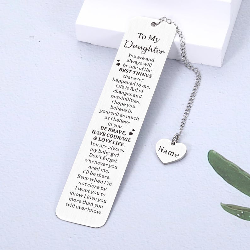 May include: Silver bookmark with a heart-shaped charm and a message to a daughter. The bookmark reads "To My Daughter You are and always will be one of the BEST THINGS that ever happened to me. Life is full of changes and possibilities, I hope you believe in yourself as much as I believe in you. BE BRAVE, HAVE COURAGE & LOVE LIFE. You are always my baby girl. Don't forget whenever you need me, I'll be there. Even when I'm not close by I want you to know I love you more than you will ever know."