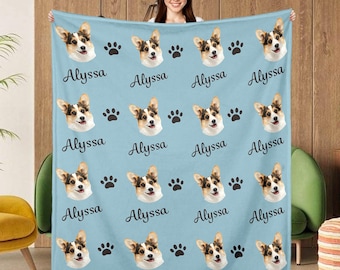 May include: A light blue fleece blanket with a repeating pattern of paw prints and a dog's face. The dog's face is a corgi with brown and white fur. The name "Alyssa" is repeated throughout the blanket.