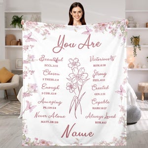 May include: White blanket featuring a floral and butterfly design. The blanket has the words "You Are" at the top, with inspirational words and Bible verses. Decorated with pink flowers and butterflies.