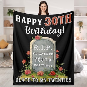 Op de afbeelding: Zwarte en witte deken met een grafsteen-afbeelding waarop staat "R.I.P. Elizabeth Youth 1994 tot 2024" en de tekst "Happy 30th Birthday! Death to my twenties".