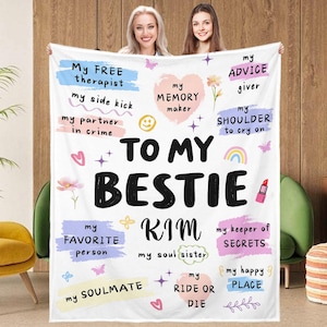 Può includere: Una coperta bianca con la scritta "TO MY BESTIE KIM" in grandi lettere nere. La coperta presenta riquadri di testo colorati con frasi come "My FREE therapist" e "My FAVORITE person". Sono presenti anche cuori, fiori e un rossetto.