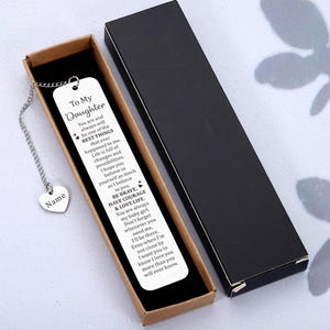 May include: A silver bookmark with a chain and heart charm. The bookmark has an inscription that reads "To My Daughter You are and always will be one of the BEST THINGS that ever happened to me. Life is full of changes and possibilities, I hope you believe in yourself as much as I believe in you. BE BRAVE, HAVE COURAGE & LOVE LIFE. You are always my baby girl. Don't forget whenever you need me, I'll be there. Even when I'm not close by I want you to know I love you more than you will ever know."