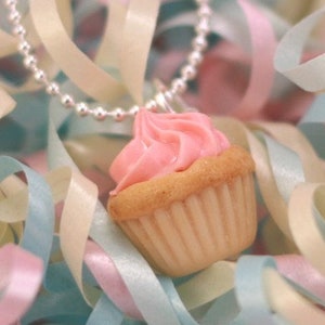 May include: A pink and white cupcake charm necklace with a silver chain. The cupcake is surrounded by pastel pink, blue, and white ribbons.