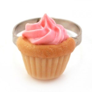 Könnte beinhalten: Ein rosafarbener und beiger Cupcake-Ring. Der Cupcake ist aus Polymer Clay gefertigt und hat einen Strudel aus rosa Zuckerguss.