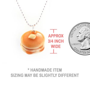 May include: A silver chain necklace with a pancake charm. The pancake is approximately 3/4 inch wide and has a small pat of butter on top. The charm is shown next to a US quarter for size comparison. Handmade item, sizing may be slightly different.