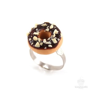 May include: A chocolate glazed donut ring with white chocolate chips, on a silver ring.