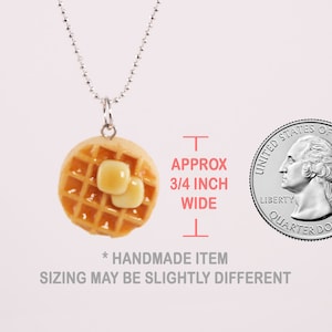 Op de afbeelding: Een zilveren ketting met een kleine, ronde, gele wafelbedel met twee klontjes boter erop. De bedel is ongeveer 3/4 inch breed. De tekst "* HANDGEMAAKT ARTIKEL DE MATEN KUNNEN LICHTS GEVARIEERD ZIJN" staat onder de bedel.