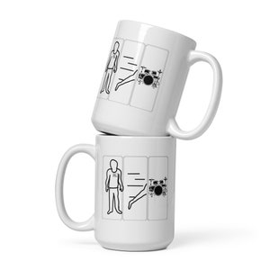May include: Two white ceramic mugs with black illustrations. The mugs feature a stick figure with the word "ALL" on their chest, a line, and a stick figure with a leg extended towards a drum set.