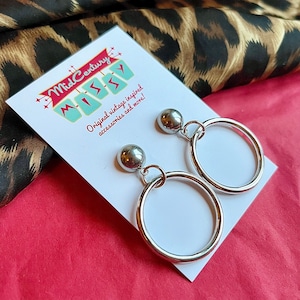 May include: Silver hoop earrings with a silver ball charm. The earrings are displayed on a white card with the text "Mid Century Missy" and "Original vintage inspired accessories and more!"