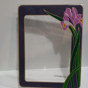 Peut inclure: Un cadre photo rectangulaire en acrylique avec une bordure violet foncé et une garniture intérieure dorée. Le côté droit du cadre est orné d'une illustration graphique d'une fleur d'iris violette avec des tiges et des feuilles vertes.
