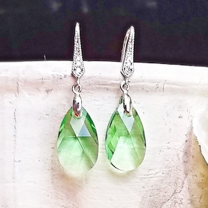 Peut inclure: Une paire de boucles d'oreilles pendantes en argent avec des pierres de cristal vertes en forme de goutte.