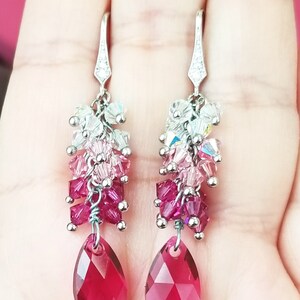 Peut inclure: Une paire de boucles d'oreilles pendantes en argent avec une cascade de perles de cristal roses, rouges et claires. Les boucles d'oreilles pr&eacute;sentent un cristal en forme de larme au bas.