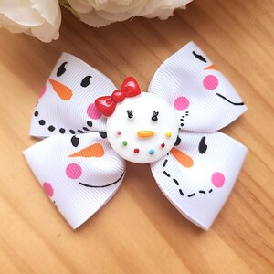 Peut inclure: Un nœud blanc avec un motif de bonhomme de neige. Le nœud présente un visage de bonhomme de neige au centre avec un nœud rouge, un nez de carotte orange et des points colorés. Les extrémités du nœud ont des visages de bonhomme de neige.