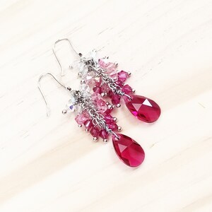 Peut inclure: Une paire de boucles d'oreilles pendantes argent&eacute;es avec un d&eacute;grad&eacute; de cristaux roses et transparents. Les boucles d'oreilles pr&eacute;sentent un cristal en forme de goutte d'eau au bas.