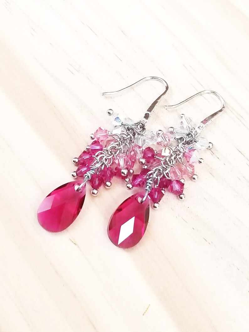 Peut inclure: Une paire de boucles d'oreilles pendantes avec des perles de cristal roses et claires et des cristaux roses en forme de goutte.