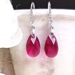 Puede incluir: Un par de pendientes de plata con piedras de cristal rojas en forma de lágrima.