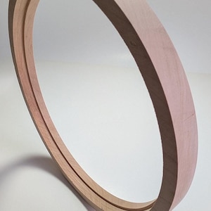 May include: A wooden hoop for a drum, with a natural wood finish.