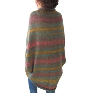 May include: A long, striped, knitted cardigan in shades of green, yellow, and pink. The cardigan has a loose fit and a high neckline.