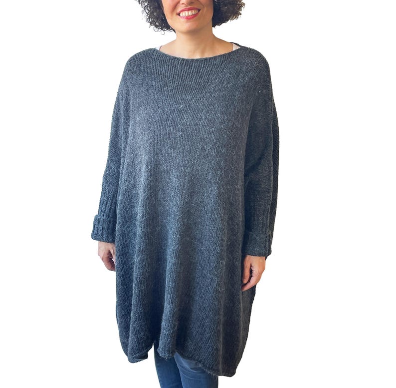 May include: A gray, oversized sweater dress with a boat neck and long sleeves. The dress has a relaxed fit and ribbed cuffs. The fabric appears to be a soft knit, perfect for cooler weather. The dress is knee-length.