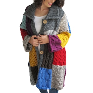 Könnte beinhalten: Ein langer, bunter Strickcardigan mit Patchwork-Muster. Der Cardigan ist aus verschiedenenfarbigen Garnen gefertigt, darunter Rot, Blau, Gelb und Lila. Er hat einen großen Kragen und zwei Holzknöpfe.