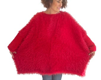Puede incluir: Un suéter rojo brillante de gran tamaño con una apariencia esponjosa y texturizada. El suéter tiene mangas largas y un cuello redondo. El material suave y difuso crea un aspecto acogedor y cálido. Esta prenda única es perfecta para agregar un toque de color a cualquier atuendo.