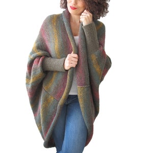 May include: A long, open-front cardigan with a striped pattern in shades of green, brown, yellow, and red. The cardigan has a relaxed fit and long sleeves.