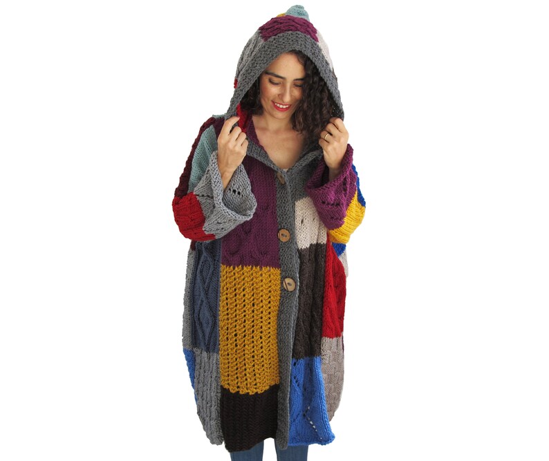 May include: A colorful patchwork cardigan with a hood, featuring a variety of knit textures and a button closure.