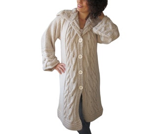 May include: A long, beige knitted cardigan with a cable knit pattern and a large collar. The cardigan has a button closure and is made of a soft, warm material.