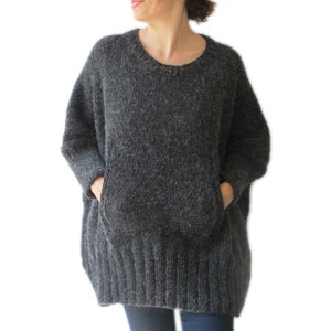 May include: A gray oversized sweater with two large pockets. The sweater is made of a soft, fuzzy material.