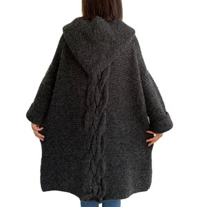 May include: A dark gray hooded cardigan with a cable knit pattern down the back.
