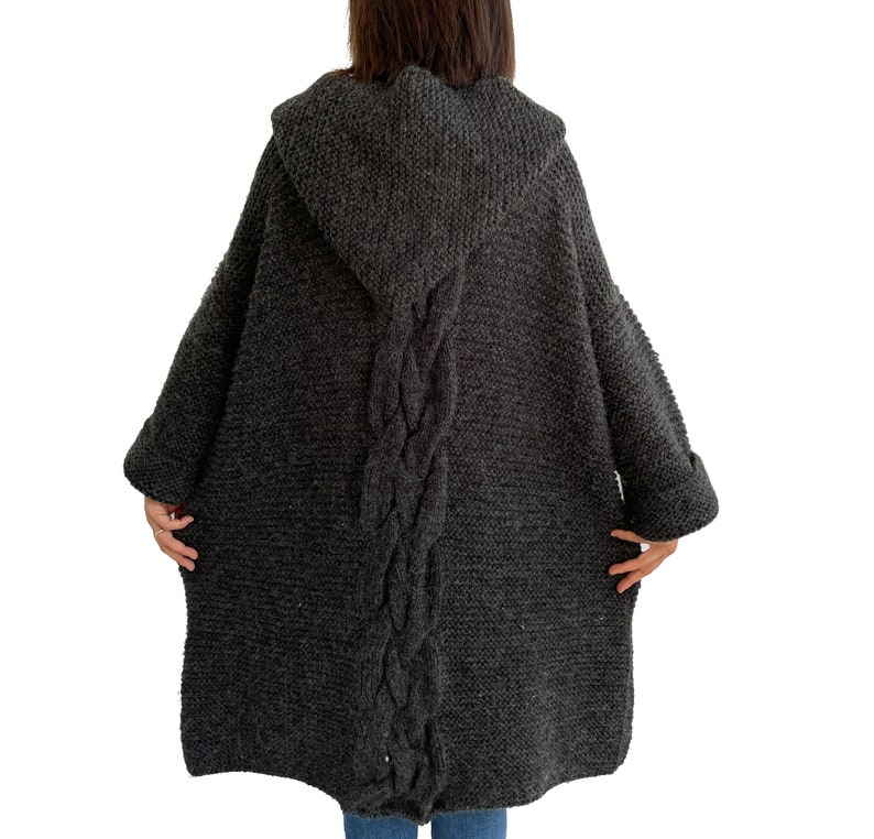 May include: A dark gray hooded cardigan with a cable knit pattern down the back.