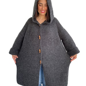 May include: A long, gray hooded cardigan with wooden buttons. The cardigan has a relaxed fit and is made of a soft, knitted fabric.