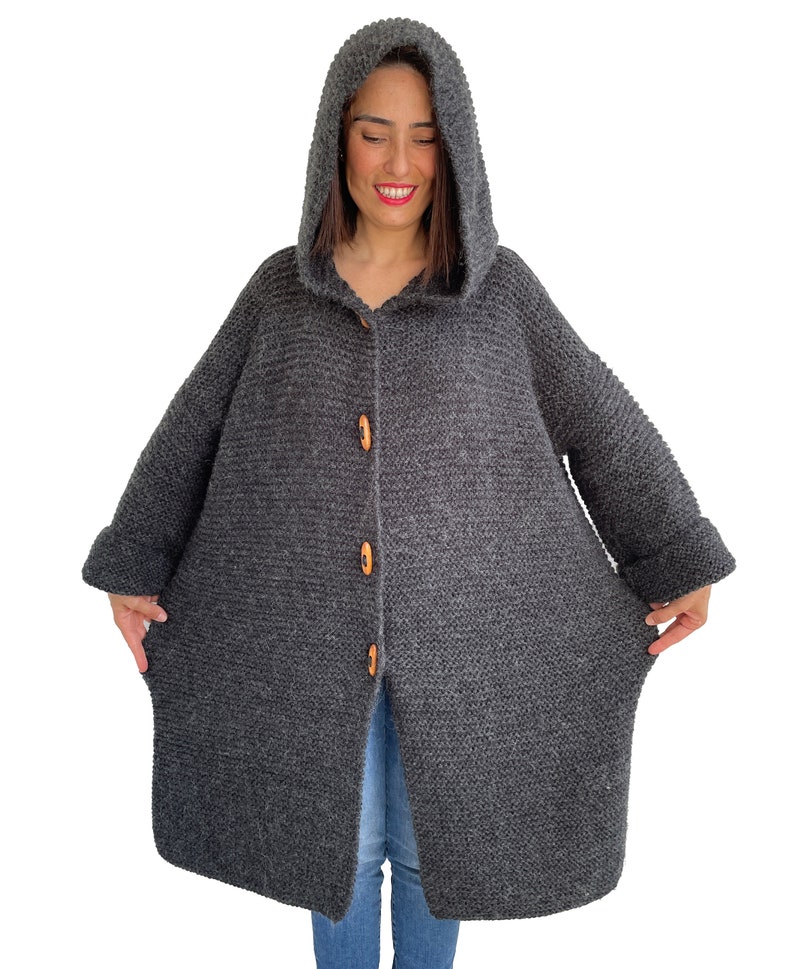May include: A long, gray hooded cardigan with wooden buttons. The cardigan has a relaxed fit and is made of a soft, knitted fabric.