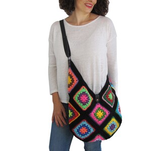 May include: A black crochet shoulder bag with a colorful geometric pattern. The bag has a black leather strap.