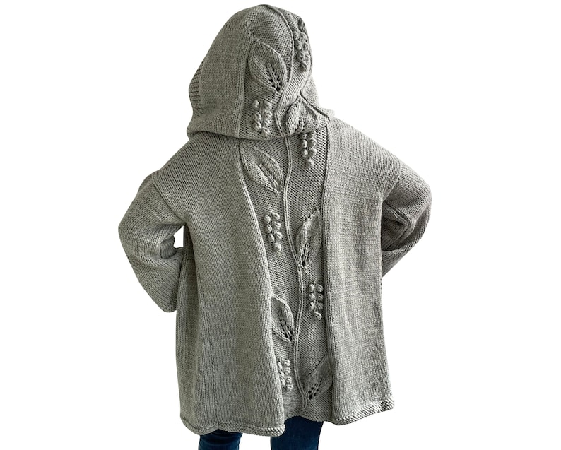 K&ouml;nnte beinhalten: Ein grauer Kapuzenpullover mit einem in den R&uuml;cken gestrickten Blatt- und Beerenmuster.