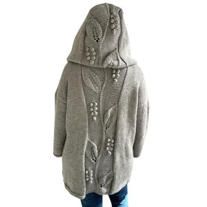 K&ouml;nnte beinhalten: Ein grauer Kapuzenpullover mit einem in den R&uuml;cken gestrickten Blatt- und Beerenmuster. Der Pullover ist aus weichem, dickem Garn gefertigt.
