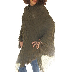 May include: A green knitted poncho with a cable knit pattern and fringe trim.