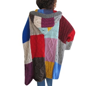 May include: A long, hooded cardigan with a patchwork design. The cardigan is made of different colored yarns, including red, blue, purple, brown, and gray.