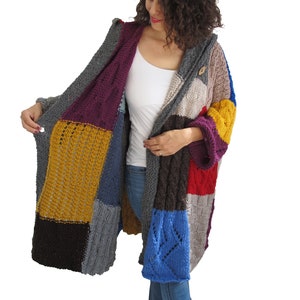 May include: A long, multi-colored knitted cardigan with a hood. The cardigan is made of different colored squares of knit fabric, including purple, yellow, blue, red, and brown. The cardigan has a button closure at the neck.