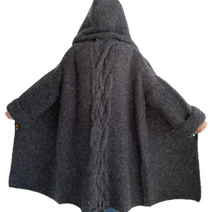 May include: A long, gray hooded cardigan with a cable knit design down the back. The cardigan has a relaxed fit and is made of a soft, cozy material.