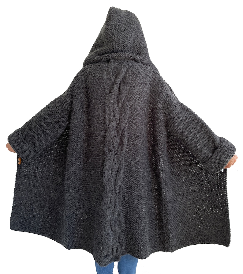 May include: A long, gray hooded cardigan with a cable knit design down the back. The cardigan has a relaxed fit and is made of a soft, cozy material.