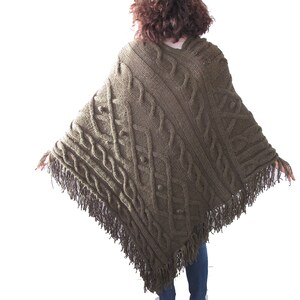 May include: A green knitted poncho with a cable knit pattern and fringe trim.