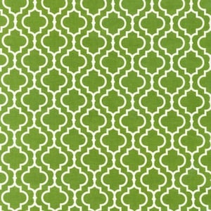 May include: A close-up of a green fabric with a white quatrefoil pattern. The repeating design creates a geometric, symmetrical look. The fabric has a textured appearance, suggesting it may be used for upholstery or home decor.
