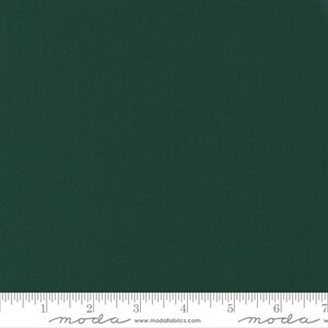 May include: A solid dark green fabric with a textured surface. A ruler is at the bottom of the image, with the word "moda" printed on it. The fabric is suitable for quilting, sewing, and various craft projects.