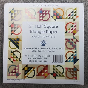 May include: A pad of 40 sheets of 2-inch Half Square Triangle Paper by Laundry Basket Quilts. The paper features a repeating pattern of colorful geometric designs. The text on the paper states it is simple to sew, accurate to cut, and effortless to remove.